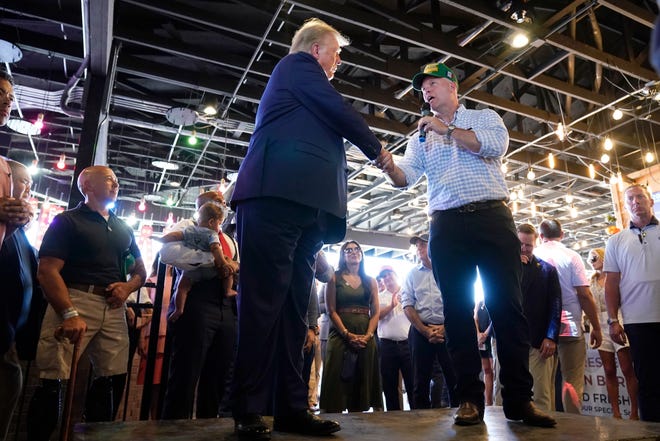 Republican presidential candidate former President Donald Trump greets former acting U.S. Attorney General Matthew Whitaker during a visit to the Iowa State Fair, Saturday, Aug. 12, 2023, in Des Moines, Iowa. (AP Photo/Charlie Neibergall)