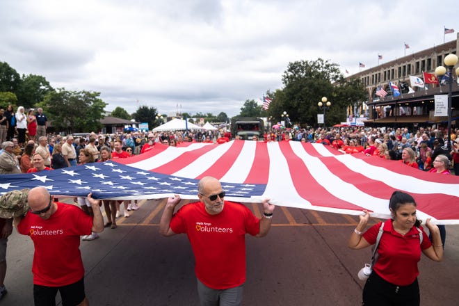 Volunteers carry a giant flag down the Grand Concourse of the Iowa State Fair during the Veteran's Day Parade, on Monday, Aug. 14, 2023, in Des Moines.