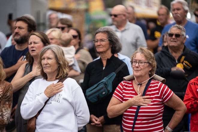 People in the crowd put their hands on their hearts while the national anthem is sung during the Iowa State Fair Veteran's Day Parade, on Monday, Aug. 14, 2023, in Des Moines.