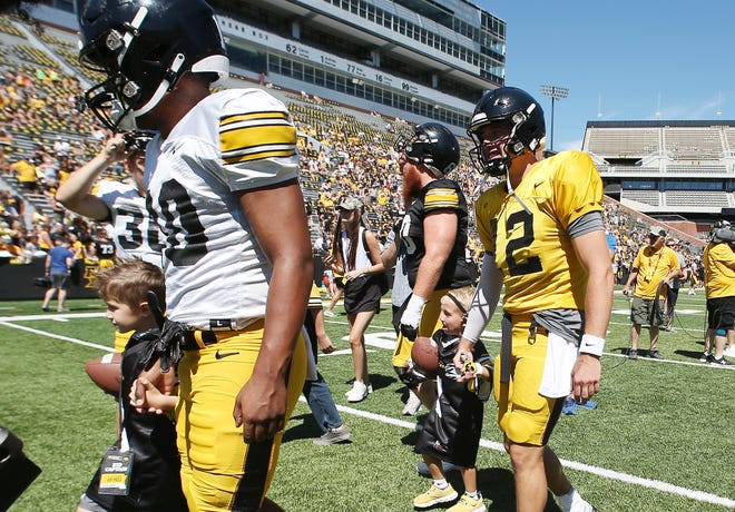 Iowa quarterback Cade McNamara (12) walks with kid captains at Kinnick Stadium during the Kids' Day at Kinnick annual event on Saturday, Aug. 12, 2023, in Iowa City.